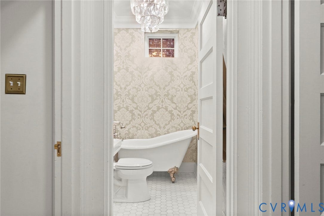 2416 Park Avenue, #U4, The Fan District, Richmond, VA 23220 Clawfoot soaking tub with metallic feet, patterned wall covering, crystal chandelier, and hexagonal tile flooring