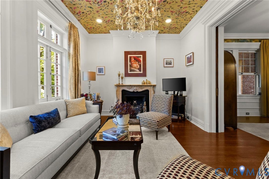 2416 Park Avenue, #U4, The Fan District, Richmond, VA 23220 Living room featuring an ornate stone fireplace mantel, multi-pane windows, wood-finish flooring, patterned ceiling wallpaper, and a central crystal chandelier