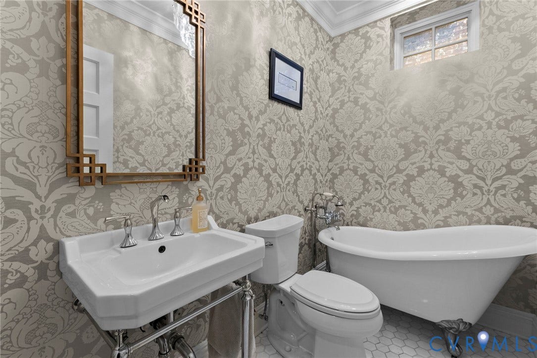 2416 Park Avenue, #U4, The Fan District, Richmond, VA 23220 Wall-mounted console sink with exposed plumbing, classic clawfoot soaking tub, patterned wallpaper, wall-mounted mirror with geometric frame, and hexagonal floor tiling