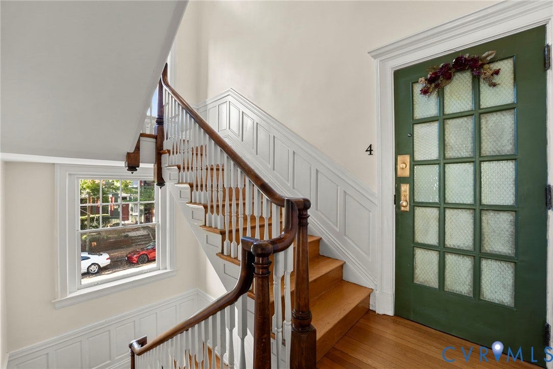 2416 Park Avenue, #U4, The Fan District, Richmond, VA 23220 Entryway featuring a green-painted paneled door with glass inserts, wood-finish staircase with a turned wooden banister, wall paneling, and wood-finish flooring