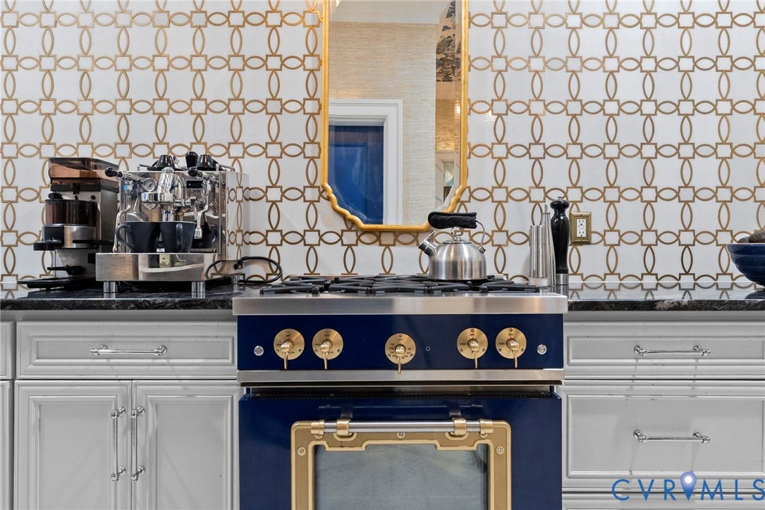 2416 Park Avenue, #U4, The Fan District, Richmond, VA 23220 Custom cabinetry with silver-tone hardware, dark stone-finish countertops, geometric-patterned wall tile, and a professional-grade blue and gold-tone gas range