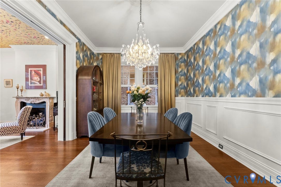2416 Park Avenue, #U4, The Fan District, Richmond, VA 23220 Dining room featuring intricate crown molding, extensive wainscoting, a crystal chandelier, wood-finish flooring, and a decorative fireplace with carved mantle