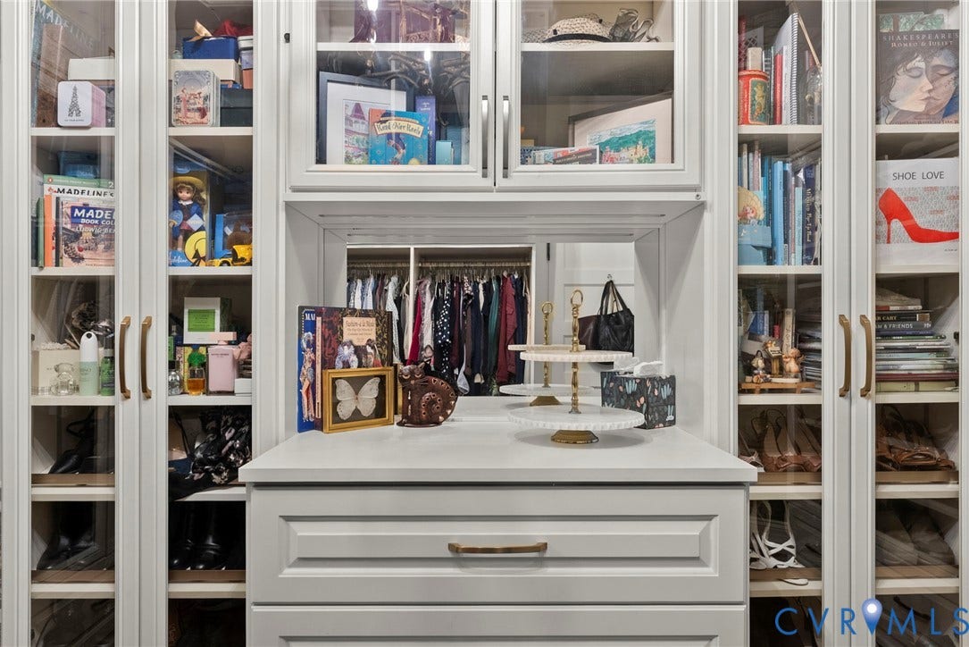2416 Park Avenue, #U4, The Fan District, Richmond, VA 23220 Built-in cabinetry featuring white shaker-style doors, glass-paneled display shelving, integrated vanity surface with mirror, and metallic hardware