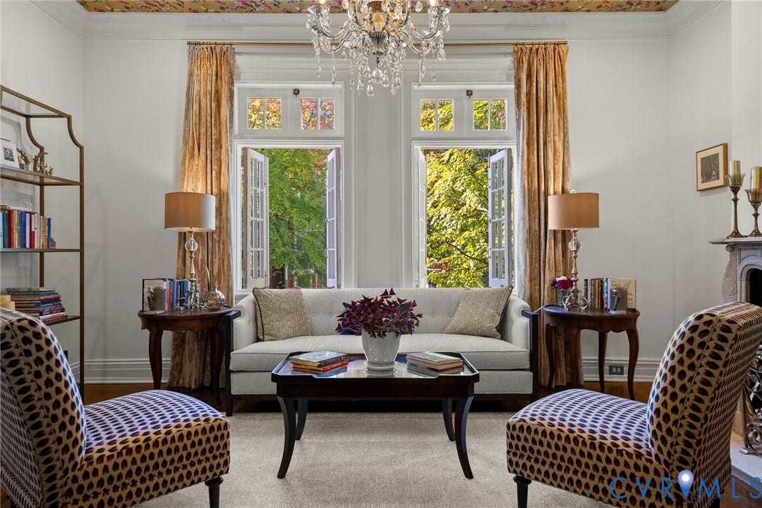 2416 Park Avenue, #U4, The Fan District, Richmond, VA 23220 Living space featuring a crystal chandelier, intricate patterned ceiling detail, dual casement windows with arched transoms, and a classic fireplace mantel