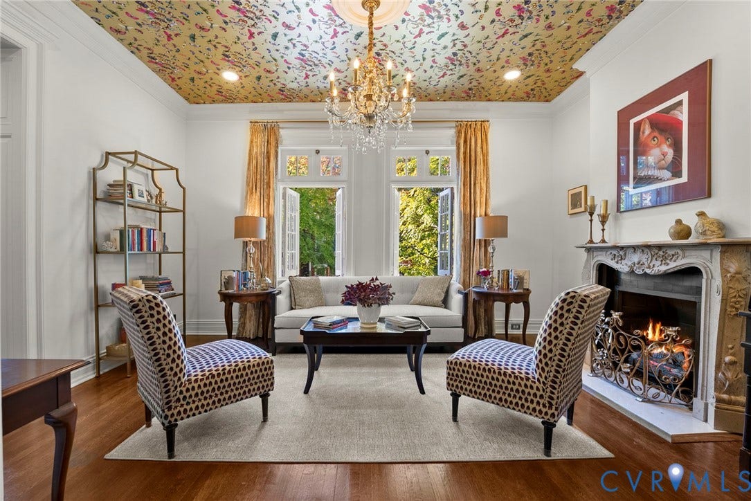 2416 Park Avenue, #U4, The Fan District, Richmond, VA 23220 Living space featuring patterned ceiling wallpaper, ornate crystal chandelier, hardwood flooring, and a decorative carved fireplace surround with a metal hearth screen