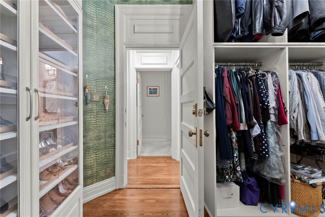 2416 Park Avenue, #U4, The Fan District, Richmond, VA 23220 Custom built-in wardrobe cabinetry with glass-front shelving, textured green accent wall covering, multi-panel interior door with brass hardware, and hardwood flooring
