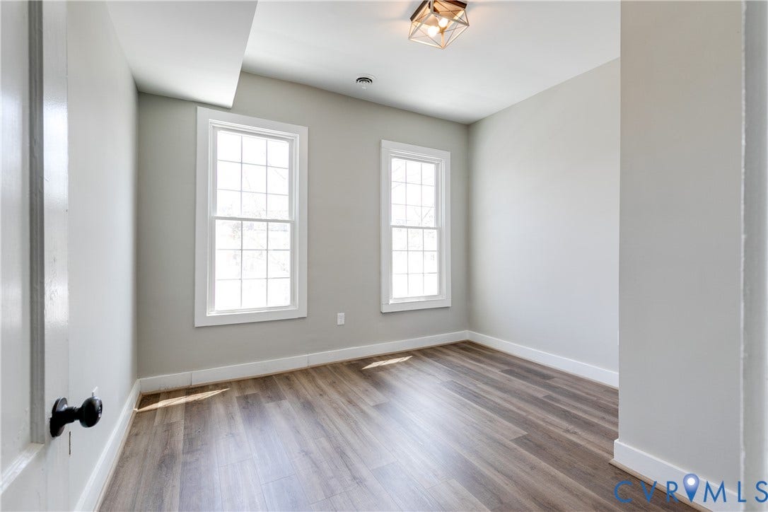 620 Chimborazo Boulevard, Church Hill, Richmond, VA 23223 Neutral interior room featuring wood-finish flooring, two grid-pattern windows, and a geometric metal flush-mount light fixture