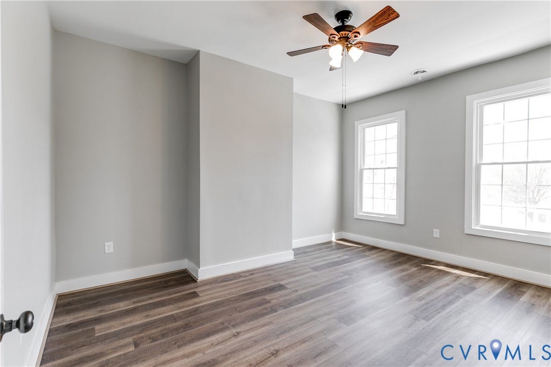620 Chimborazo Boulevard, Church Hill, Richmond, VA 23223 Neutral-toned room featuring wood-finish flooring, dual grid-pattern windows, and a ceiling fan with integrated lighting