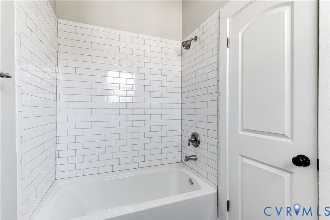 620 Chimborazo Boulevard, Church Hill, Richmond, VA 23223 White subway tile surround, standard acrylic bathtub, brushed metal shower head and faucet hardware, and a white arched-panel door with a matte black handle