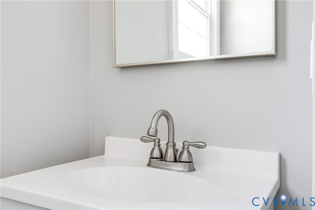 620 Chimborazo Boulevard, Church Hill, Richmond, VA 23223 White countertop with an integrated basin, paired with a brushed nickel double-handle faucet and a rectangular framed mirror