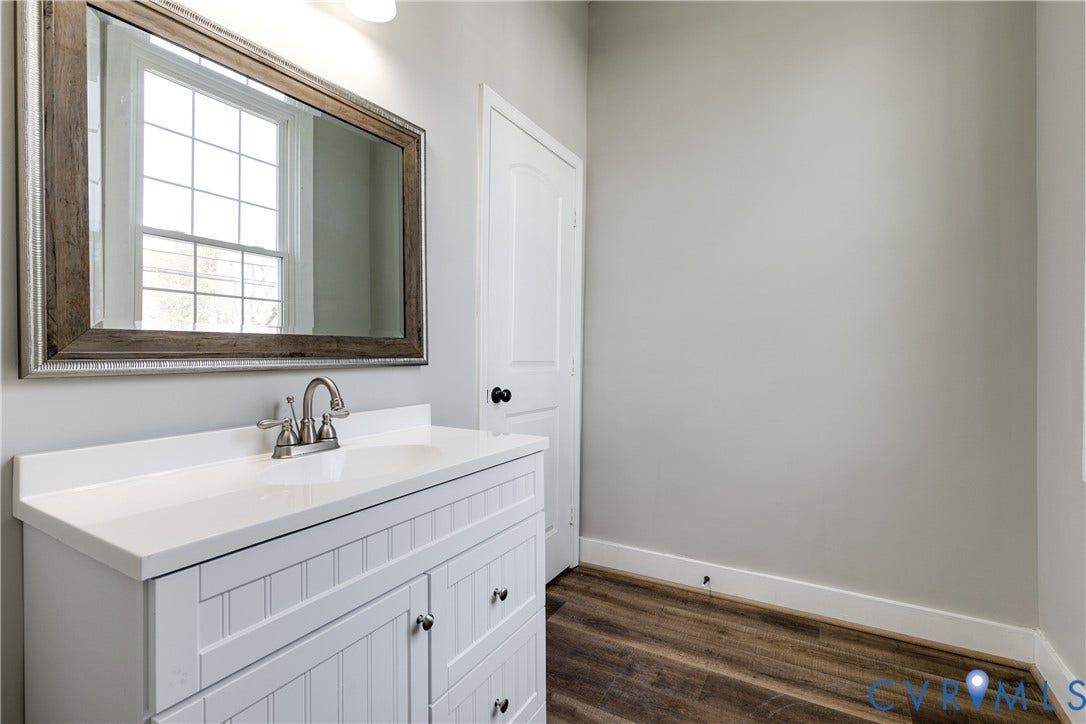 620 Chimborazo Boulevard, Church Hill, Richmond, VA 23223 White beadboard vanity with a solid countertop, integrated basin, brushed metal faucet, and wood-finish flooring