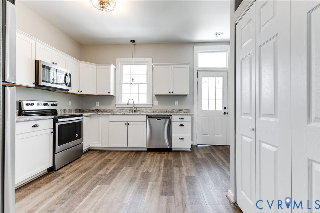 620 Chimborazo Boulevard, Church Hill, Richmond, VA 23223 Kitchen featuring white cabinetry, stone-surface countertops, stainless steel appliances, wood-finish flooring, and a single-pane exterior door with a transom window