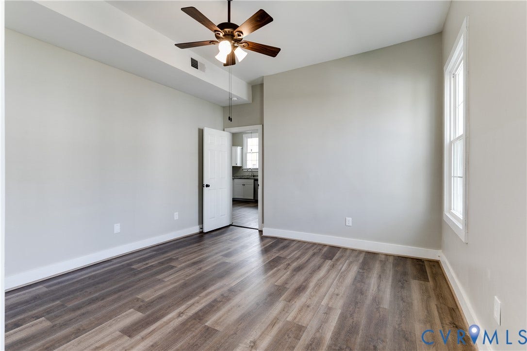 620 Chimborazo Boulevard, Church Hill, Richmond, VA 23223 Room featuring wood-finish flooring, a tray ceiling, multi-blade ceiling fan with integrated lighting, and a multi-pane window