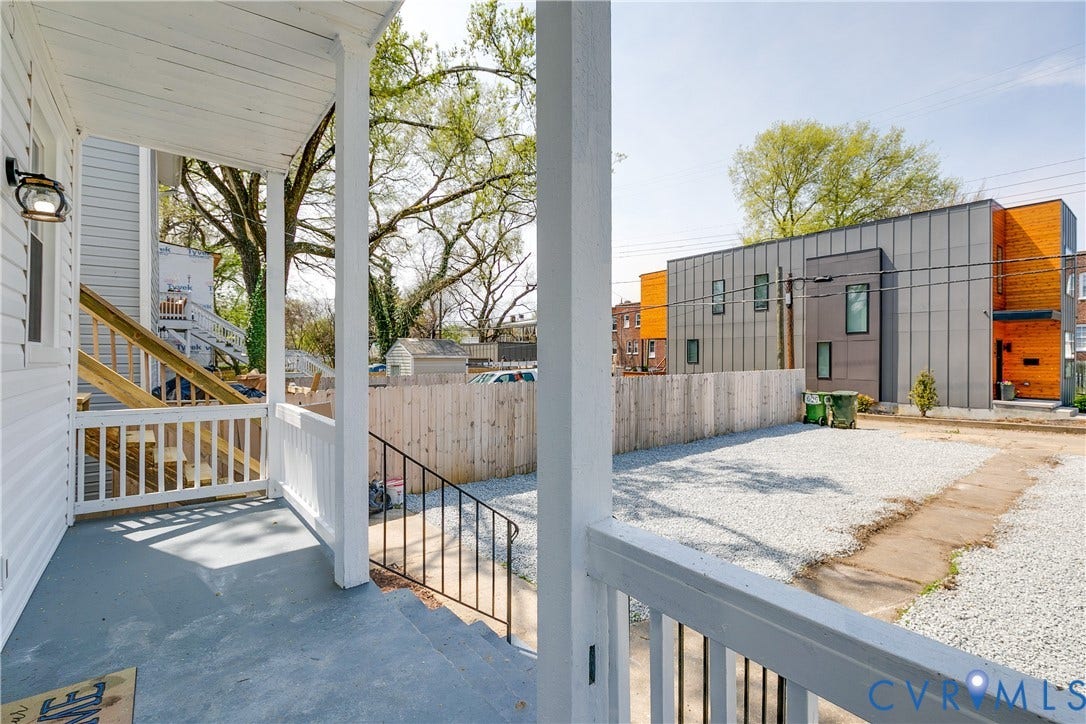 620 Chimborazo Boulevard, Church Hill, Richmond, VA 23223 Covered front porch with white railing, exterior wall-mounted light fixture, gravel parking area, and wood privacy fencing