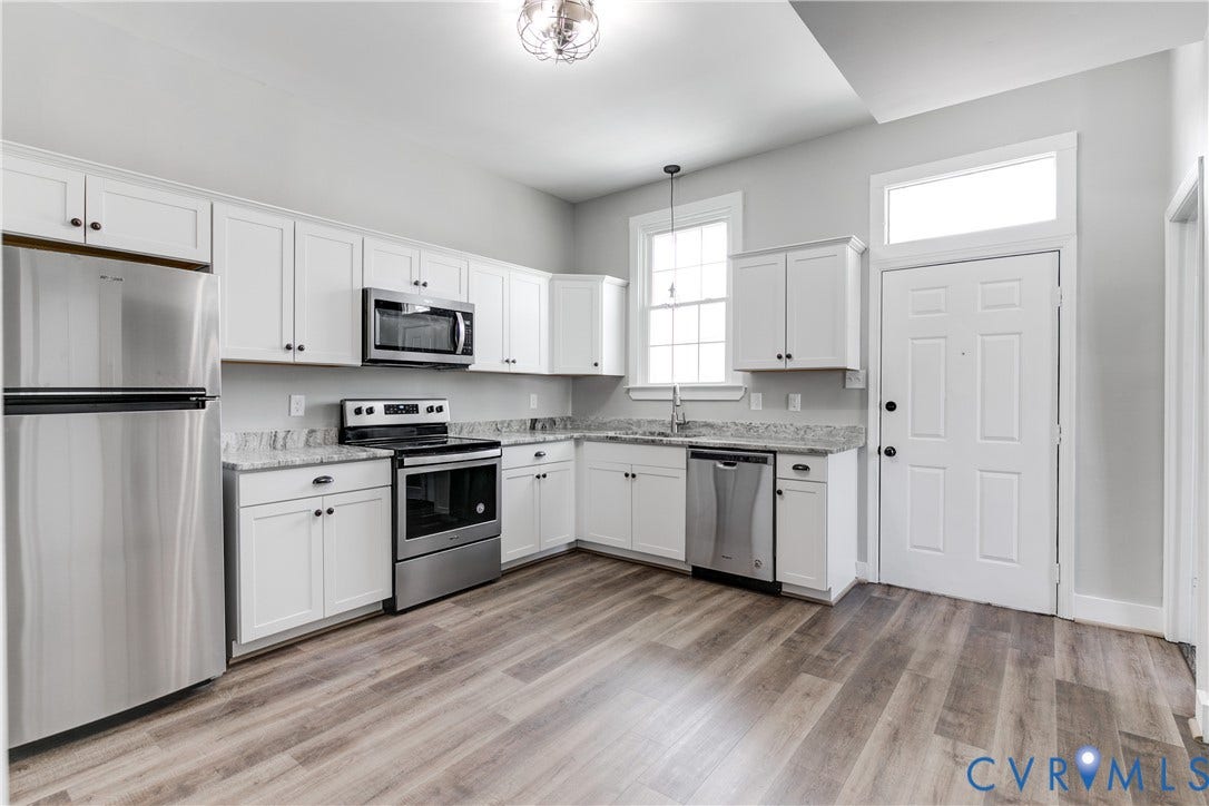 620 Chimborazo Boulevard, Church Hill, Richmond, VA 23223 Kitchen featuring shaker-style white cabinetry, stone-finish countertops, stainless steel appliances, wood-finish flooring, and a transom window above the door