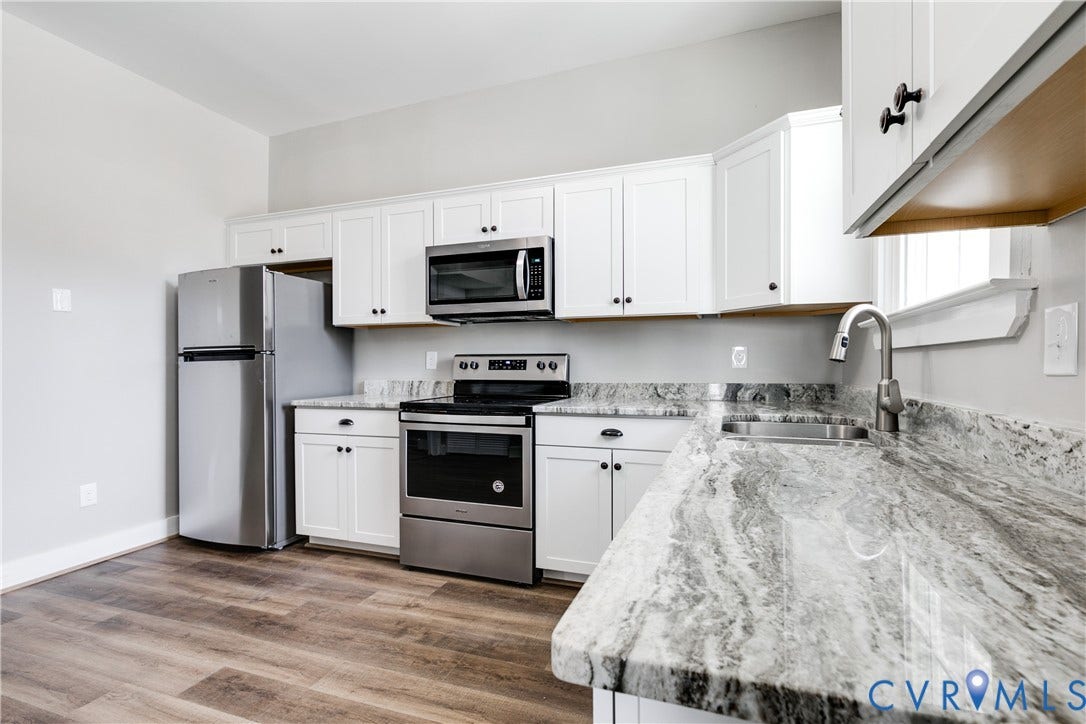 620 Chimborazo Boulevard, Church Hill, Richmond, VA 23223 Kitchen featuring white shaker-style cabinetry, high-contrast stone countertops, stainless steel appliances, and wood-finish flooring
