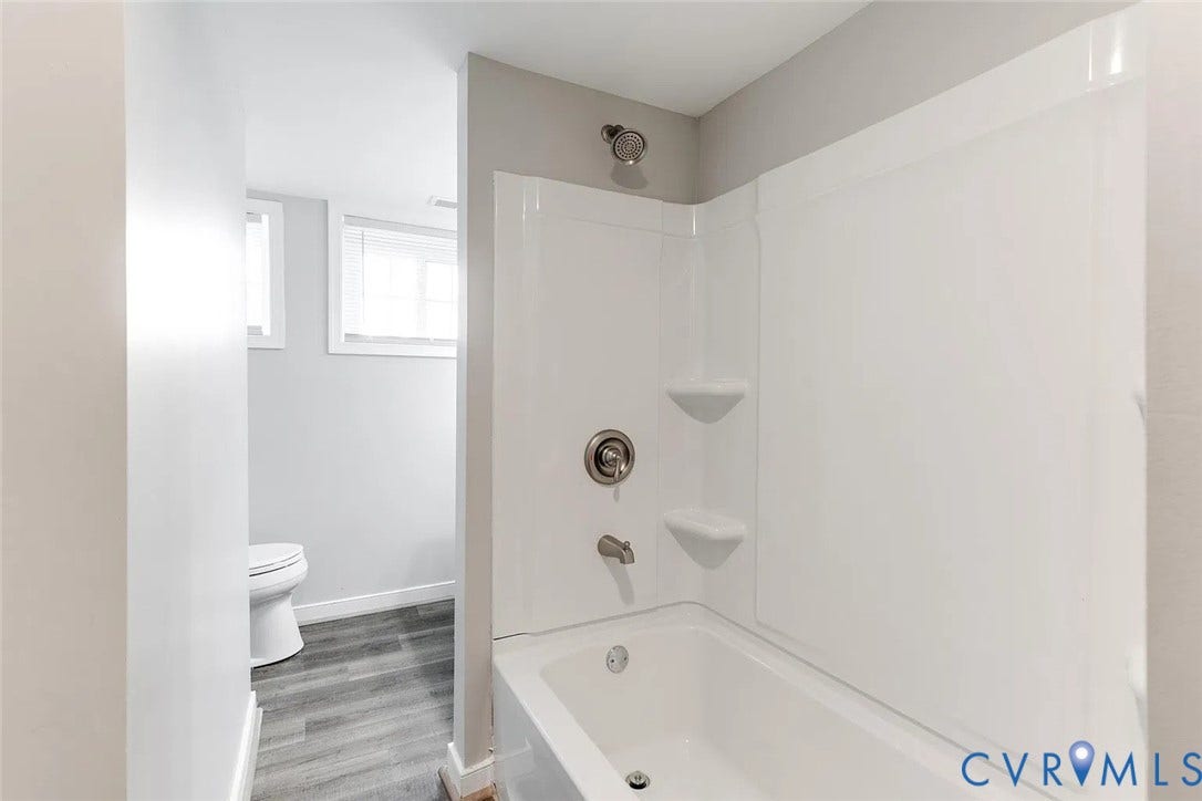 620 Chimborazo Boulevard, Church Hill, Richmond, VA 23223 Bathroom featuring a tub-shower combination with integrated shelving, metallic finish hardware, wood-finish flooring, and white cabinetry