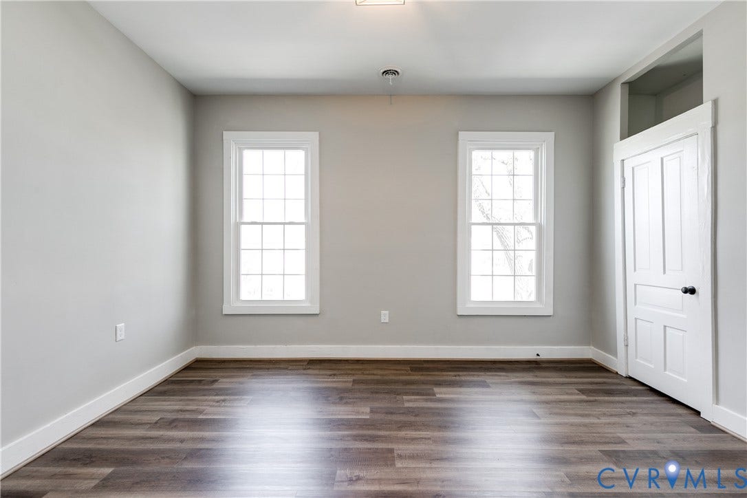 620 Chimborazo Boulevard, Church Hill, Richmond, VA 23223 Room featuring wood-finish flooring, two multi-pane windows with white trim, neutral wall paint, and a classic four-panel door with a transom window