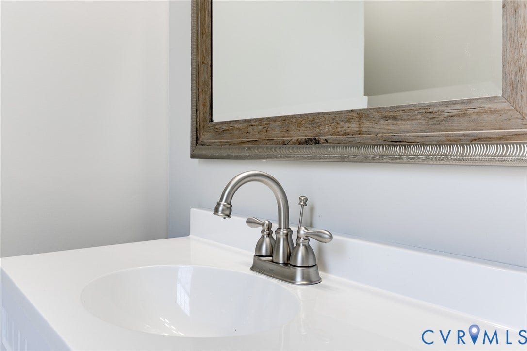 620 Chimborazo Boulevard, Church Hill, Richmond, VA 23223 Integrated vanity featuring a solid-surface countertop, an oval undermount sink, a dual-handle brushed nickel faucet, and a decorative wood-finish framed wall mirror