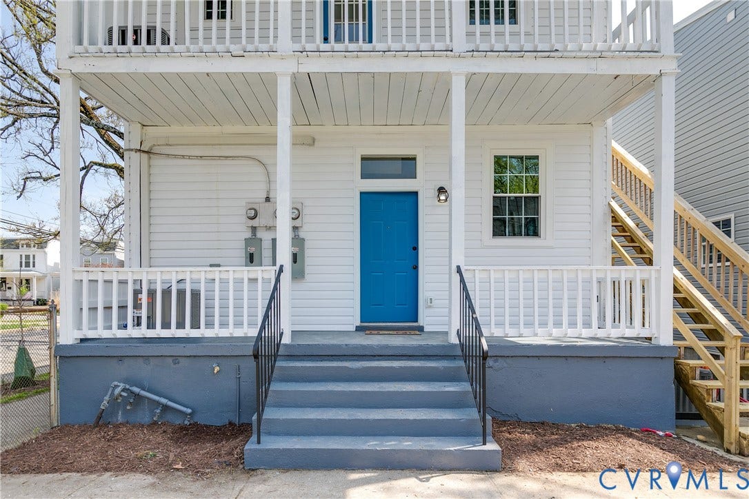 620 Chimborazo Boulevard, Church Hill, Richmond, VA 23223 Exterior featuring dual-level covered porches with white railing, blue paneled entrance door, single-hung window with transom, and wooden staircase