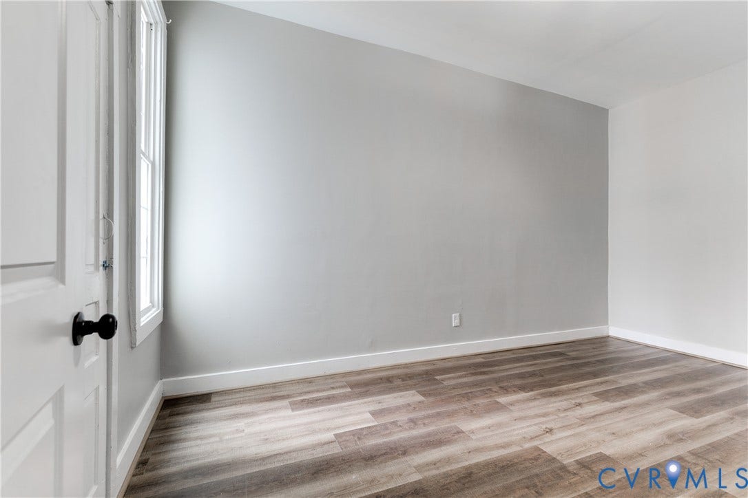 620 Chimborazo Boulevard, Church Hill, Richmond, VA 23223 Neutral-toned walls, wood-finish flooring, and a multi-pane window with a black-finished handle, featuring a white paneled door with a matte black lever handle