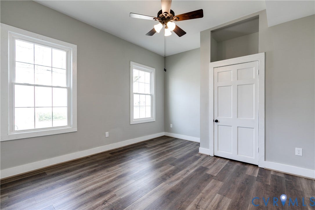 620 Chimborazo Boulevard, Church Hill, Richmond, VA 23223 Interior space featuring wood-finish flooring, two multi-pane windows, a recessed wall niche above a six-panel door, and a ceiling fan with integrated lighting