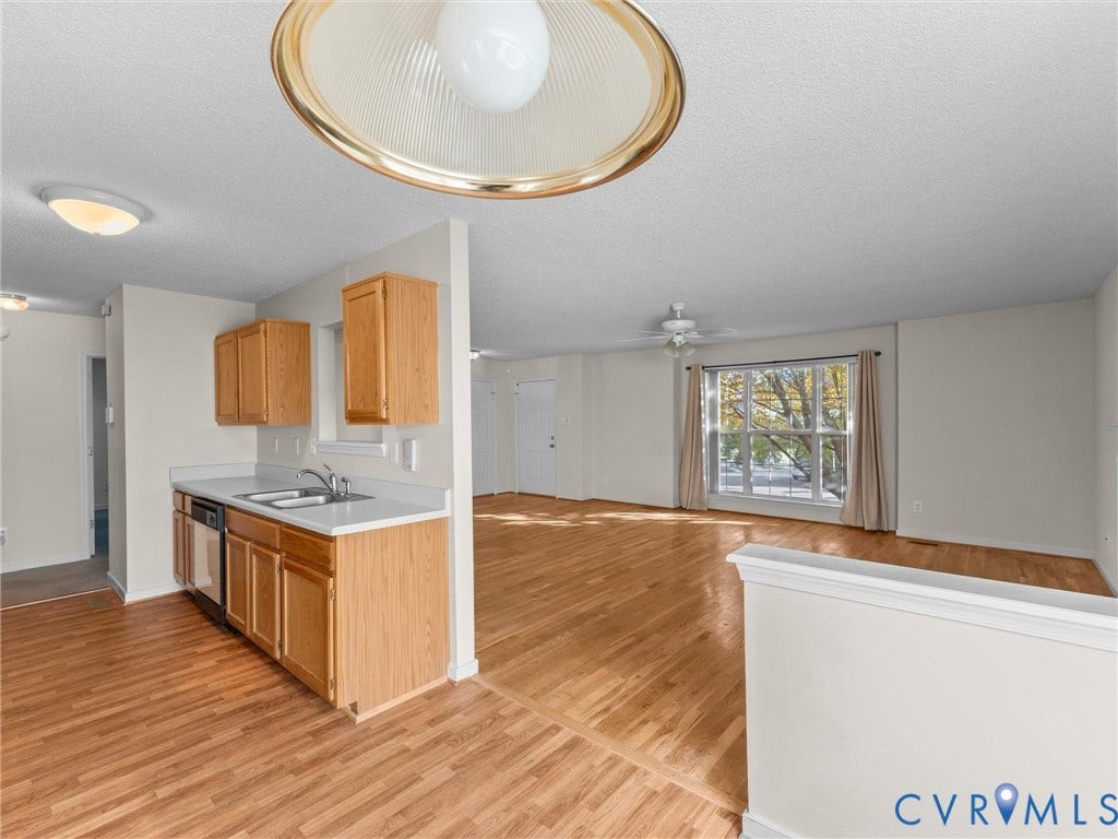 9520 Willow Ridge Drive, Glen Allen, VA 23060 Kitchen featuring wood-finish cabinetry, solid surface countertops, and dual-basin stainless steel sink, complemented by wood-finish flooring and a multi-light ceiling fixture