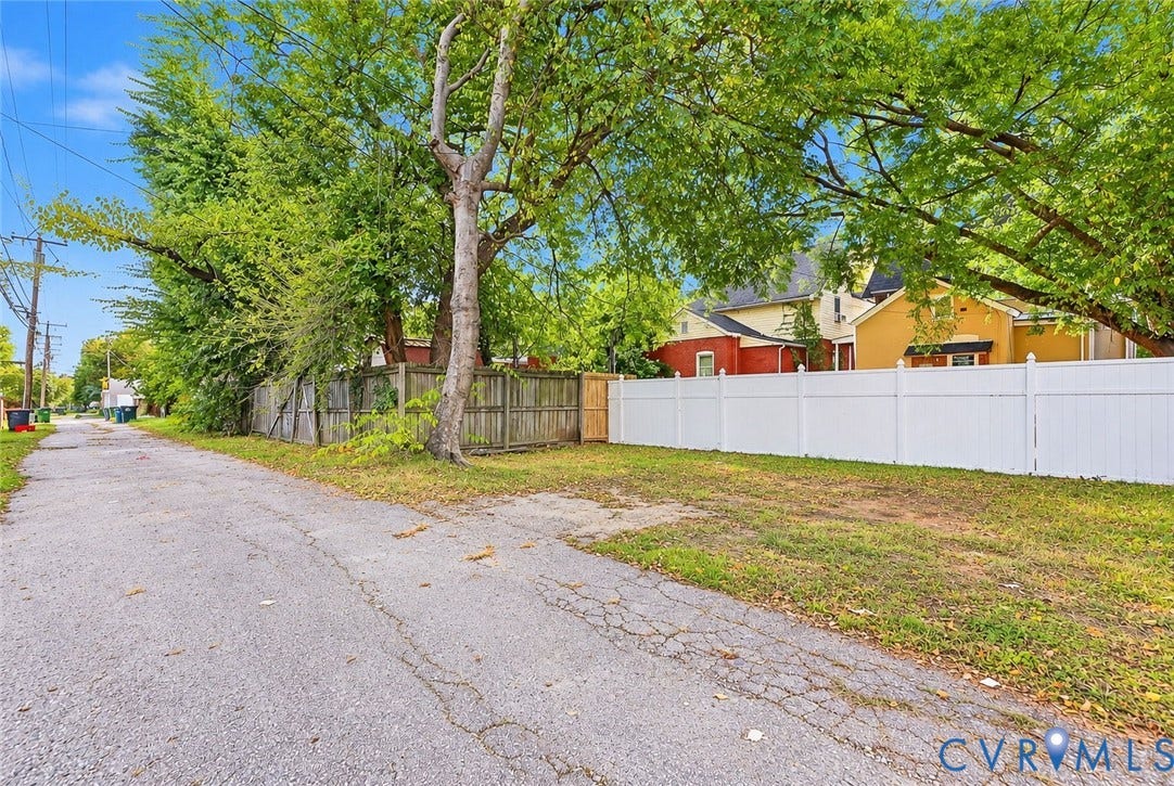 1911 3rd Avenue, Richmond, VA 23222 Exterior lot featuring white vinyl fencing, wood perimeter fencing, and mature trees