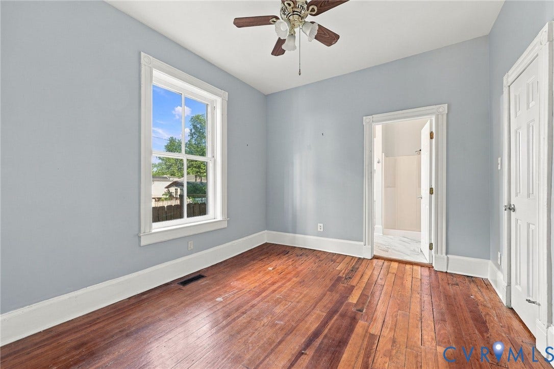 1911 3rd Avenue, Richmond, VA 23222 1st floor bedroom : Interior space featuring natural wood-finish flooring, white paneled doors with traditional millwork, and a built-in knee-wall access door