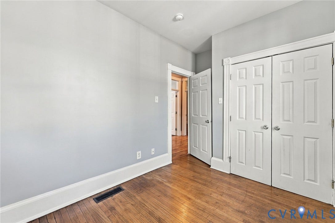 1911 3rd Avenue, Richmond, VA 23222 Room featuring wood-finish flooring, white six-panel interior doors, and double-door closet cabinetry with polished chrome hardware