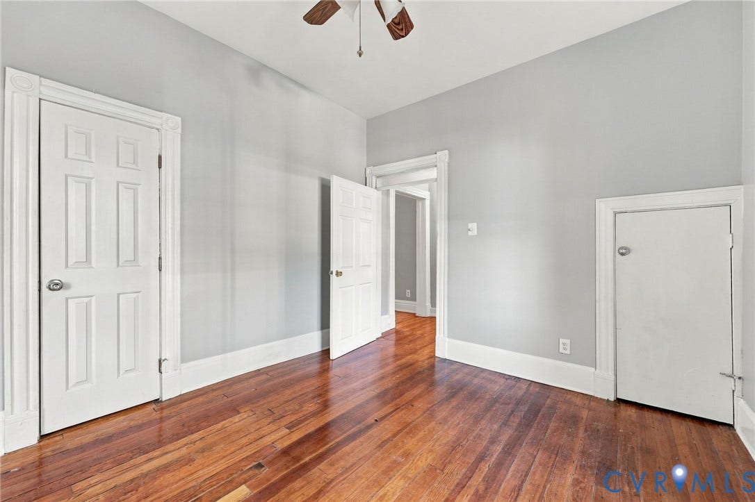 1911 3rd Avenue, Richmond, VA 23222 1st floor bedroom : Interior space featuring natural wood-finish flooring, white paneled doors with traditional millwork, and a built-in knee-wall access door