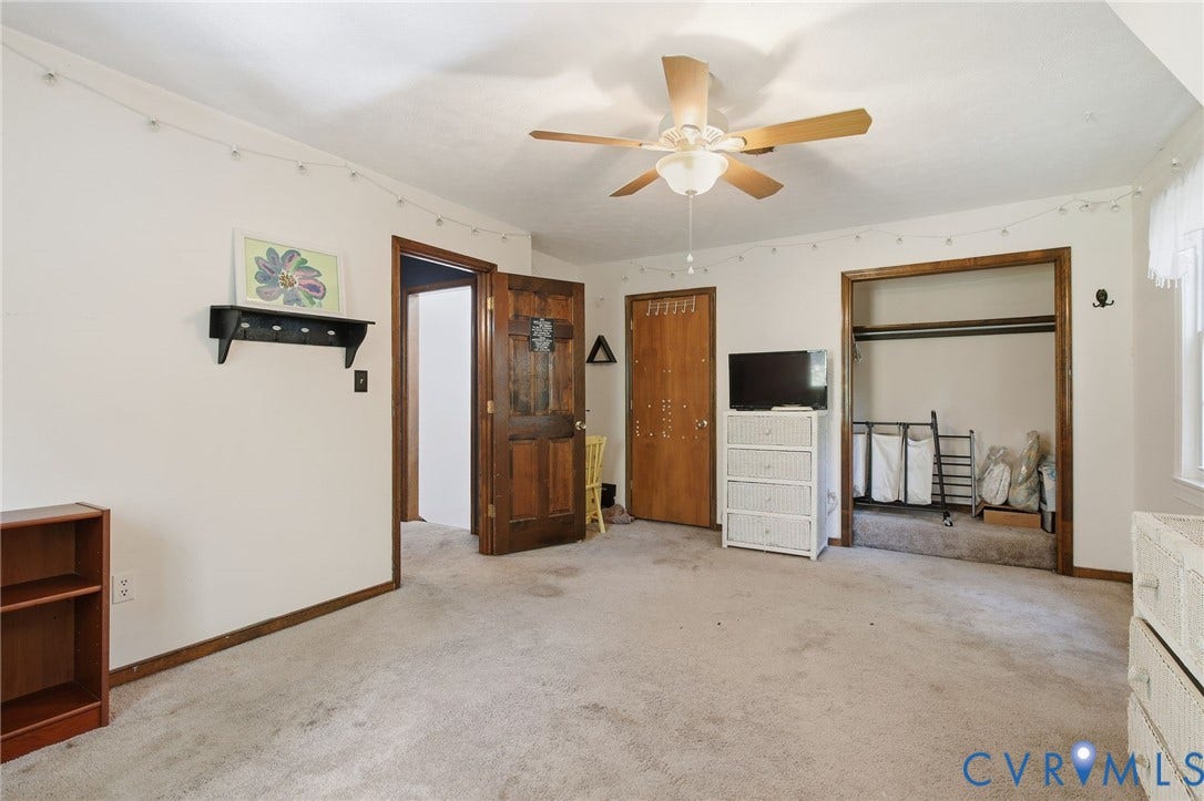 1330 Ruffin Mill Road, South Chesterfield, VA 23834 Room featuring neutral carpeting, a central ceiling fan with integrated lighting, solid wood-finish doors with stained trim, and a built-in closet with an open header