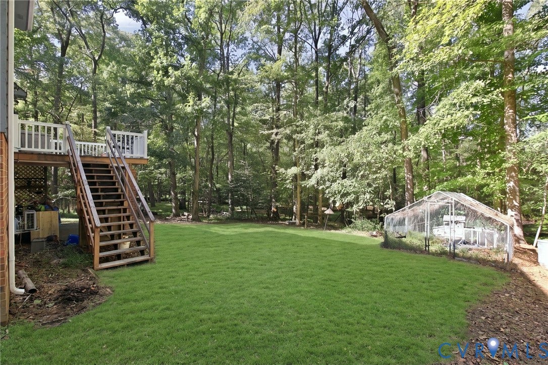1330 Ruffin Mill Road, South Chesterfield, VA 23834 Expansive backyard featuring a tiered wooden deck with white railing, wood-frame staircase, manicured lawn, and mature woodland canopy