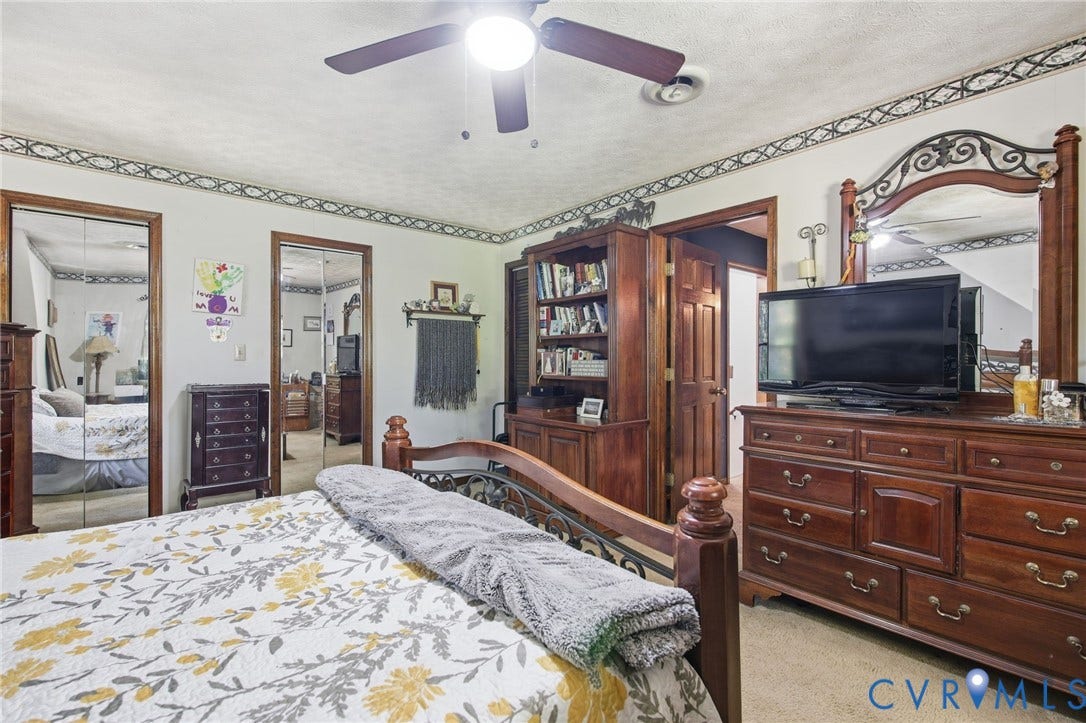 1330 Ruffin Mill Road, South Chesterfield, VA 23834 Room featuring dual mirrored closet doors, a built-in wooden shelving unit, and an overhead ceiling fan with integrated lighting