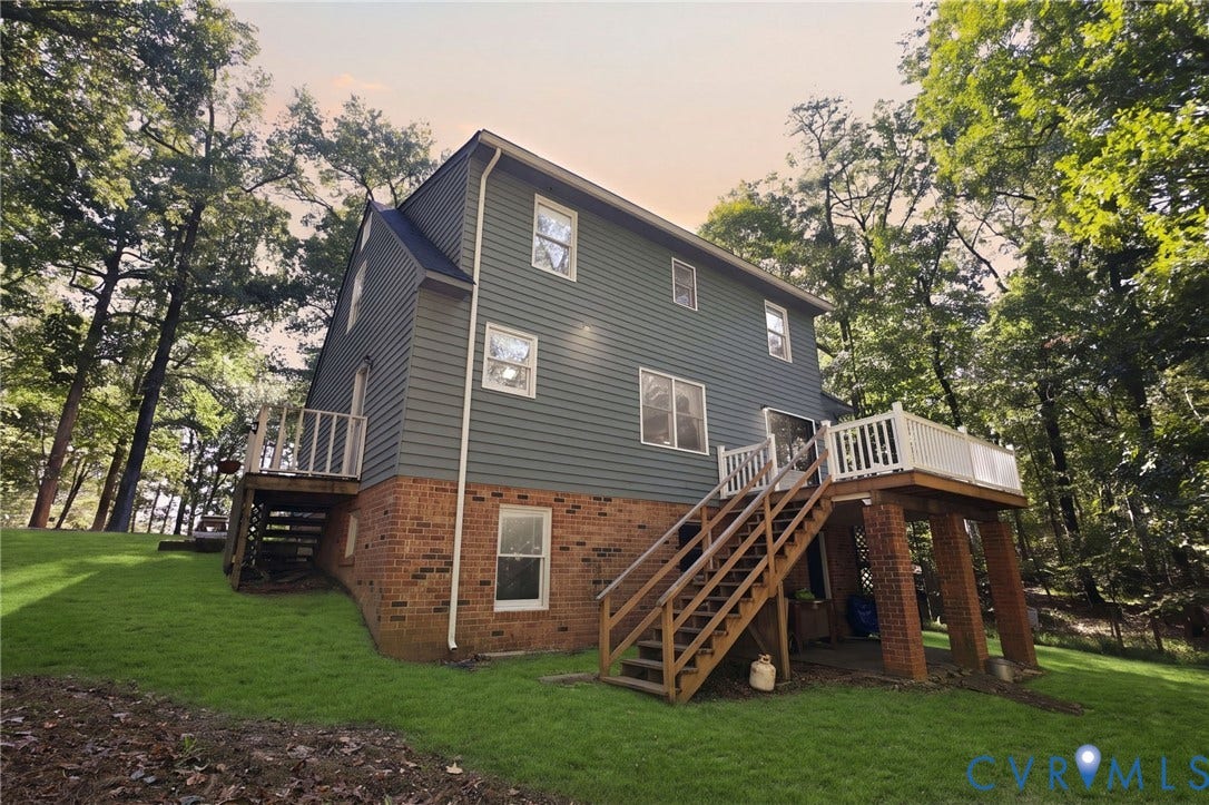 1330 Ruffin Mill Road, South Chesterfield, VA 23834 Exterior featuring a brick and horizontal siding faade, elevated rear wooden deck with white railing, and a sloped lawn surrounded by mature trees