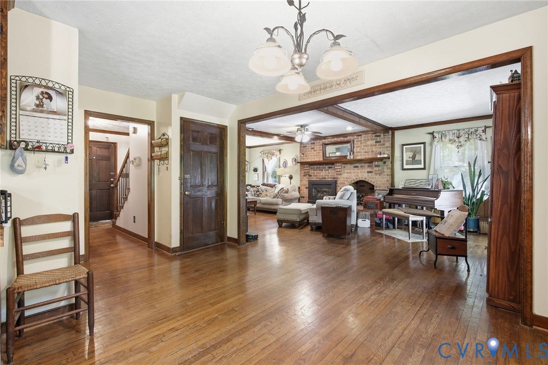 1330 Ruffin Mill Road, South Chesterfield, VA 23834 Wood flooring throughout, masonry fireplace with a brick surround and wood mantel, decorative chandelier, and stained wood door frames