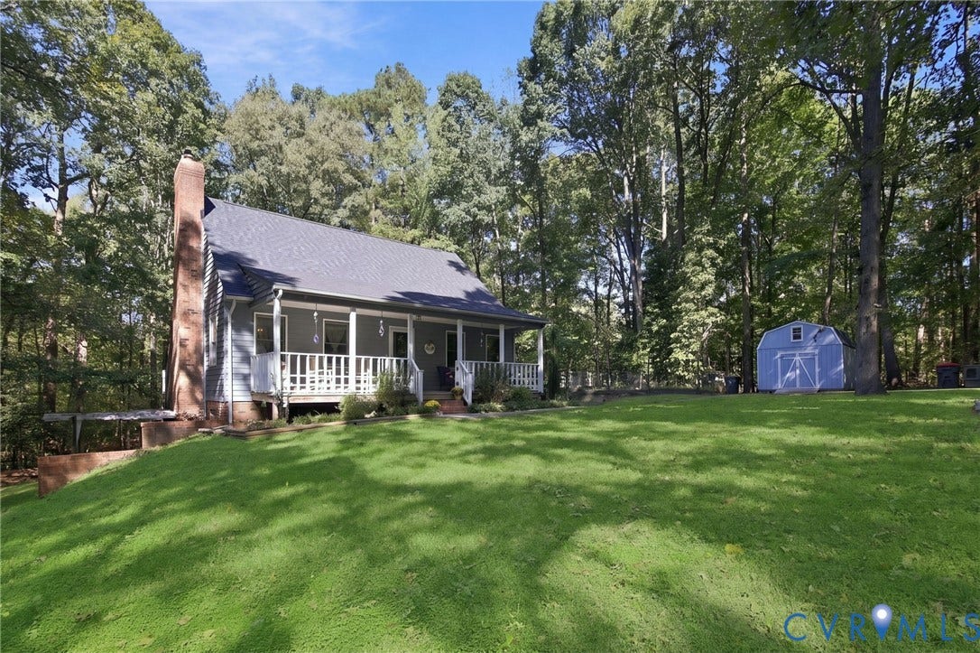 1330 Ruffin Mill Road, South Chesterfield, VA 23834 Exterior featuring a covered front porch, an external stone chimney, lap siding, and a detached storage structure set on a lot with mature trees