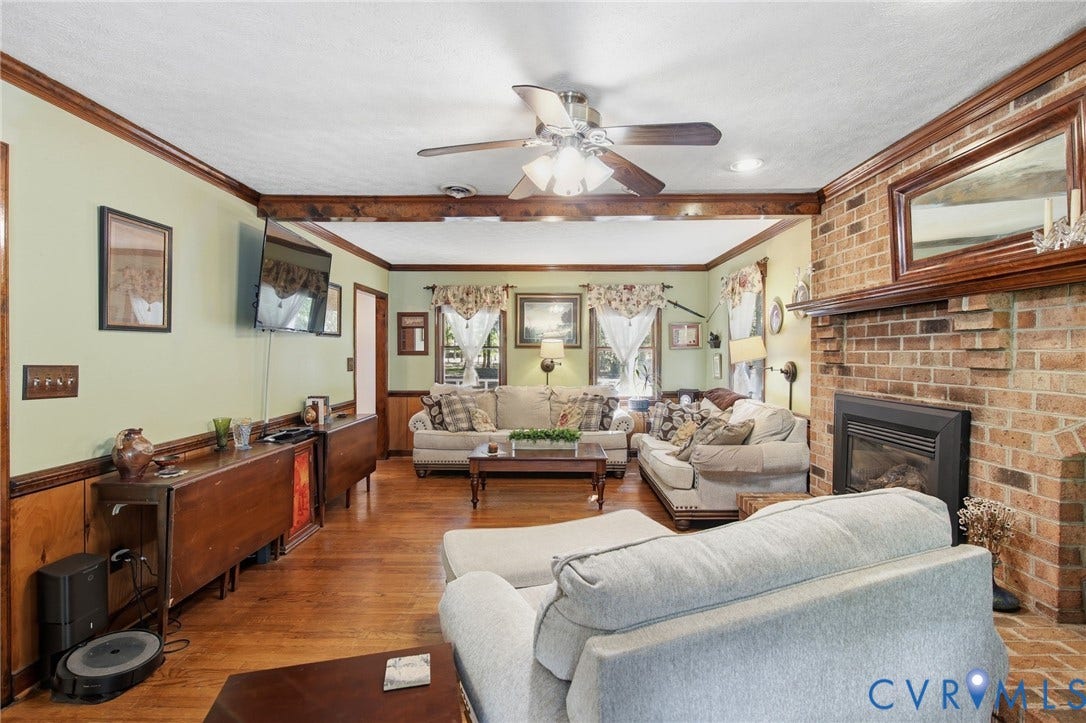 1330 Ruffin Mill Road, South Chesterfield, VA 23834 Hardwood flooring, wood-paneled wainscoting, exposed ceiling beams, and a floor-to-ceiling brick fireplace with a wood mantel