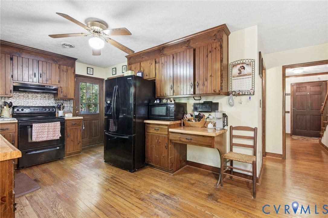 1330 Ruffin Mill Road, South Chesterfield, VA 23834 Kitchen featuring solid wood cabinetry, black appliances, a built-in desk area, and wood flooring