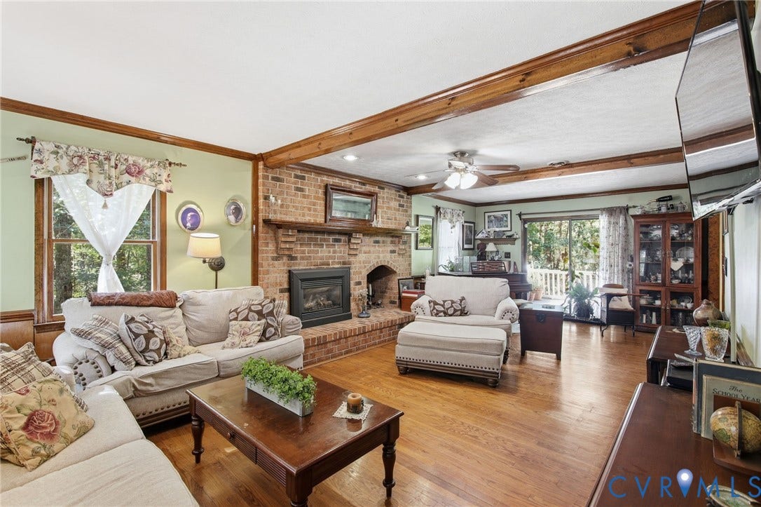 1330 Ruffin Mill Road, South Chesterfield, VA 23834 Living area featuring exposed ceiling beams, wood-finish flooring, and a floor-to-ceiling brick fireplace with a built-in mantle