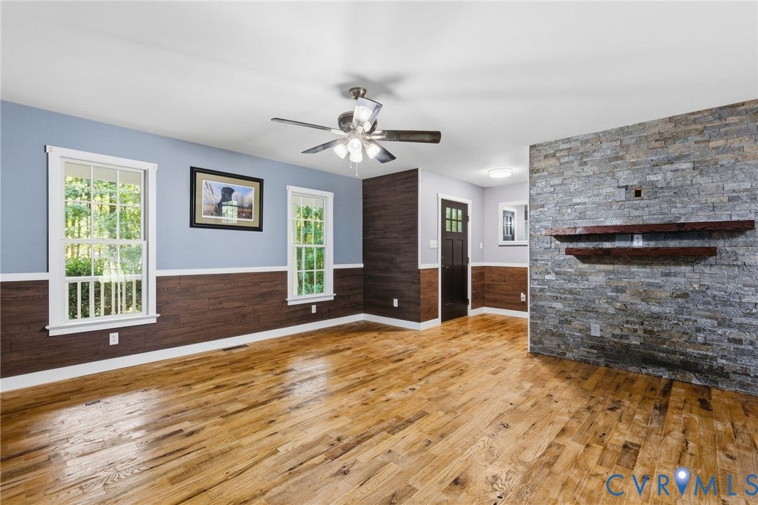 4350 Steger Creek Drive, Powhatan, VA 23139 Living area featuring wood-finish flooring, stone-veneer accent wall, horizontal wood-panel wainscoting, and a ceiling-mounted light fixture with a fan