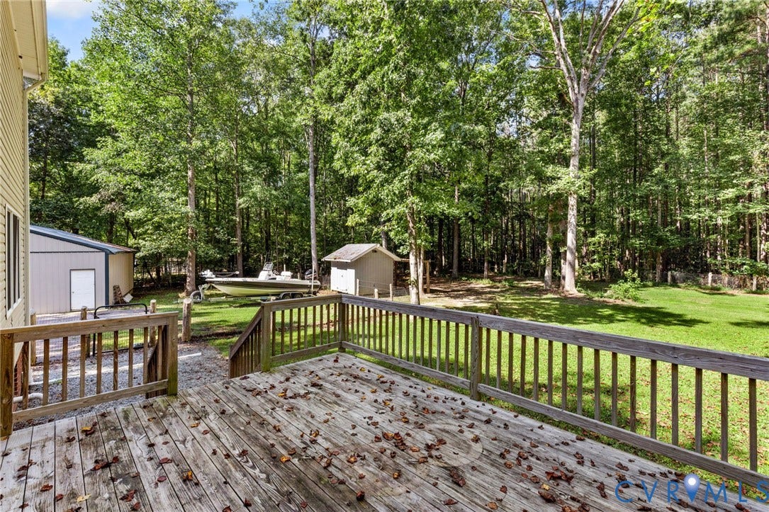 4350 Steger Creek Drive, Powhatan, VA 23139 Raised wood deck with a picket railing, expansive lawn, detached storage structure, and perimeter mature trees