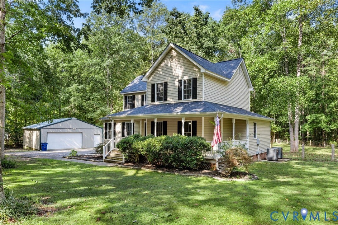 4350 Steger Creek Drive, Powhatan, VA 23139 Two-story residence featuring light-toned horizontal siding, a covered front porch with railing, dark-toned shutters, a shingled roof, and a detached metal-sided garage