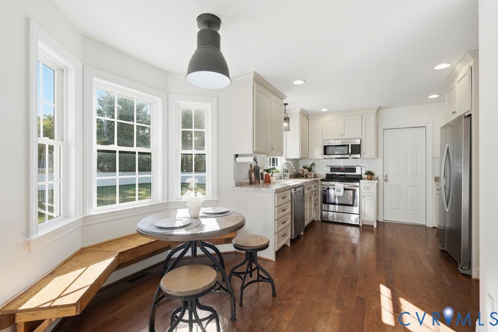 8477 Cheraw Road, Mechanicsville, VA 23116 Kitchen featuring wood-finish flooring, built-in cabinetry, stainless steel appliances, a built-in wooden dining bench, and a bay window