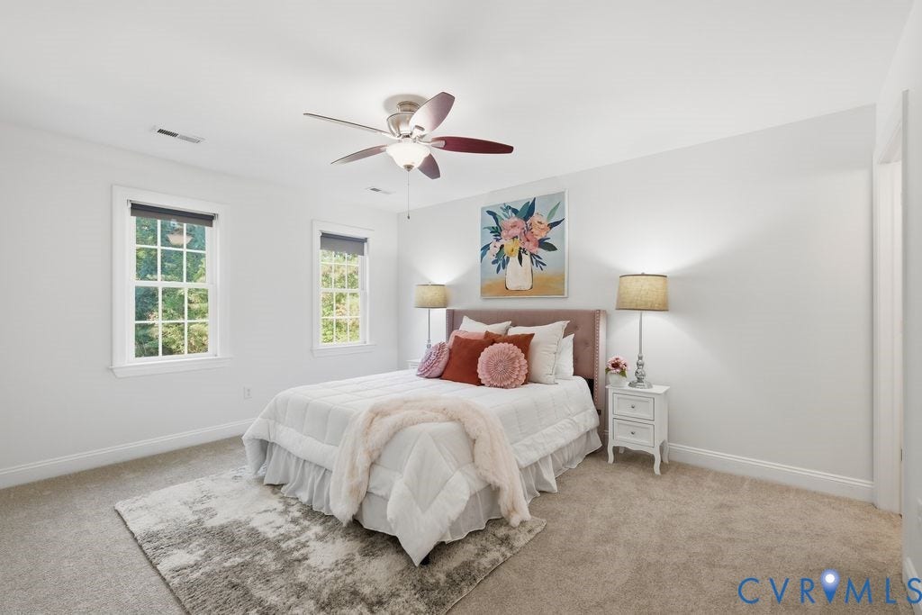 8477 Cheraw Road, Mechanicsville, VA 23116 Neutral-toned interior featuring wall-to-wall carpeting, multiple double-hung windows with exterior trim, and a ceiling-mounted light fixture with a multi-blade fan