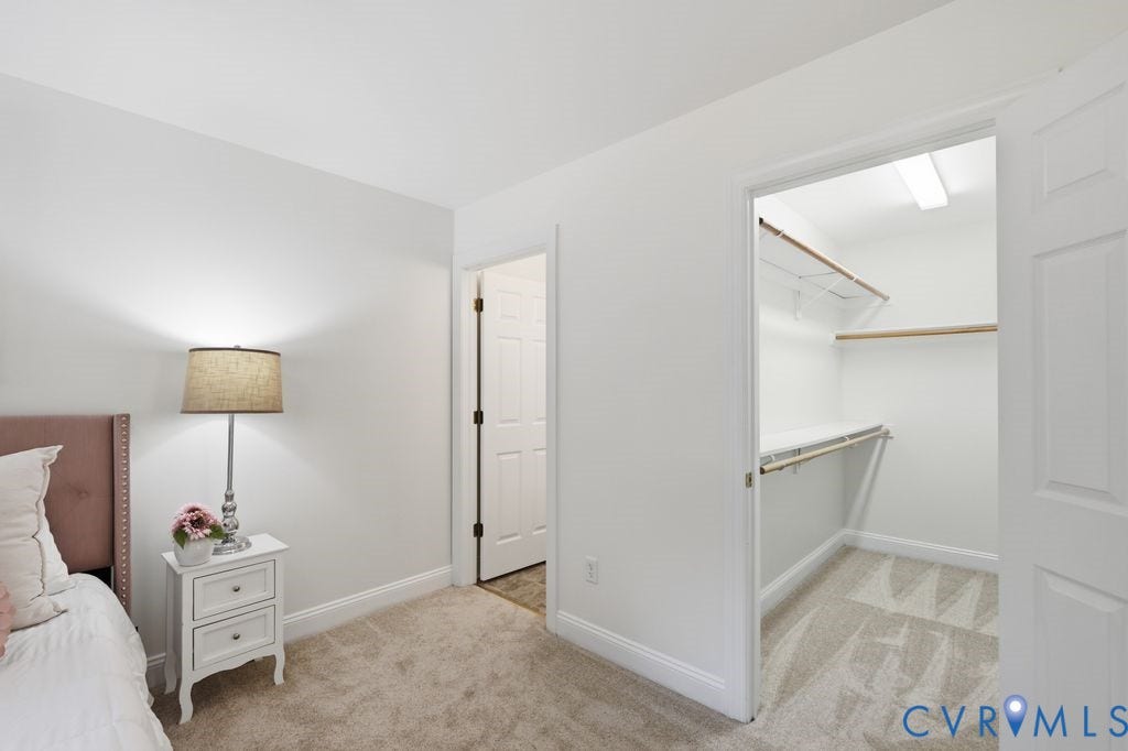8477 Cheraw Road, Mechanicsville, VA 23116 Neutral-toned carpeting, crisp white walls, six-panel interior door, and walk-in closet featuring built-in shelving