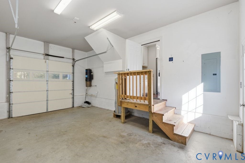 8477 Cheraw Road, Mechanicsville, VA 23116 Two-car garage featuring a sectional overhead door, built-in central vacuum system, dual flush-mount fluorescent lighting, and a raised wooden staircase with balustrade