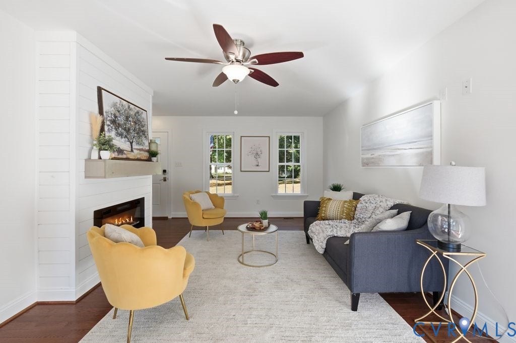 8477 Cheraw Road, Mechanicsville, VA 23116 Interior space featuring wood-finish flooring, a white shiplap fireplace surround with a mantel, multi-pane windows, and a ceiling fan with integrated lighting