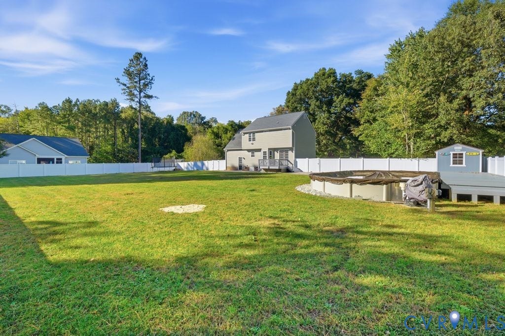 8477 Cheraw Road, Mechanicsville, VA 23116 Expansive backyard featuring a vinyl privacy fence, an above-ground pool with a surrounding deck, and a detached storage structure