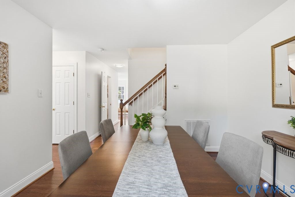 8477 Cheraw Road, Mechanicsville, VA 23116 Dining area featuring wood-finish flooring, a staircase with a wooden handrail, and white vertical balusters